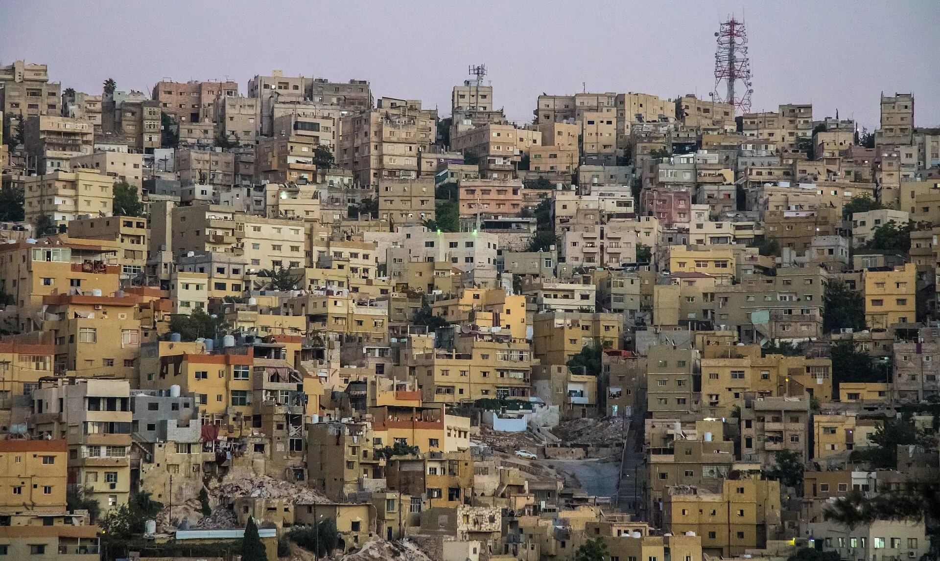 Amman at dusk, pale stone housing packed across the hillsides