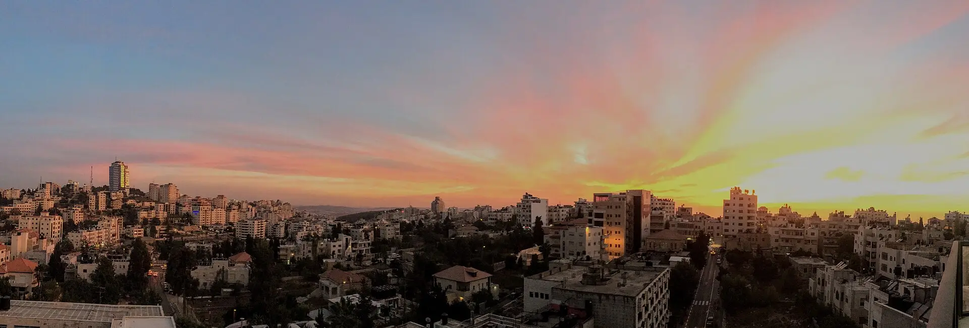 Ramallah at sunset, the city spread beneath an orange sky
